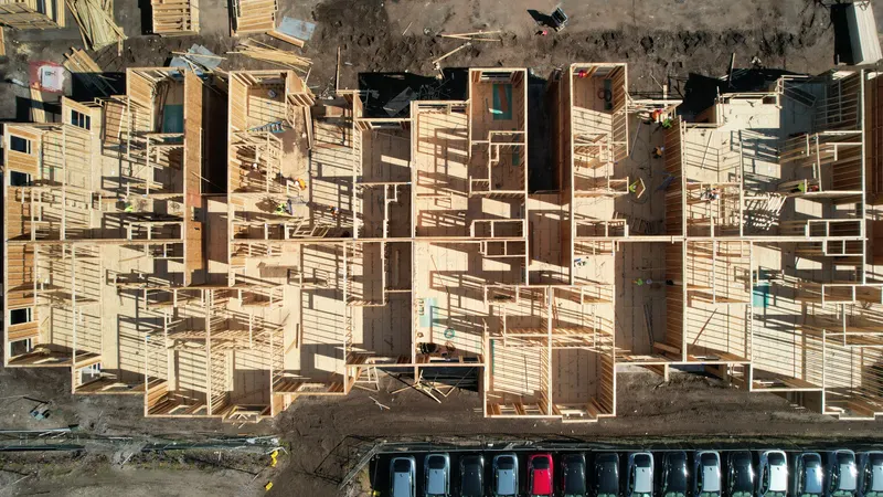 Straight-down aerial of first-floor wall framing, showing the stud-wall layout of individual units before the floor system goes on.