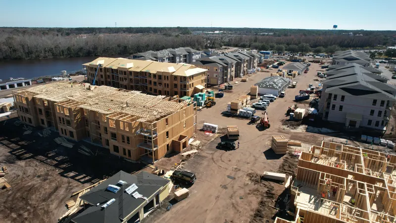 Aerial view of a building with Howland roof trusses set and partially decked, staged material alongside and completed buildings behind.